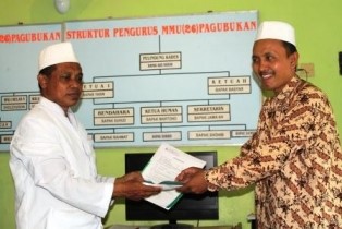 Kepala Madrasah Ibtidaiyah, Baihaqi Juri (Kiri) sedang memberikan bantuan uang tunai kepada Kepala Madrasah Ranting.