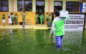 Relawan LAZ Sidogiri menuju perataran SDN SDN Kadungringin IV yang dingenangi air setingti lutut orang dewasa